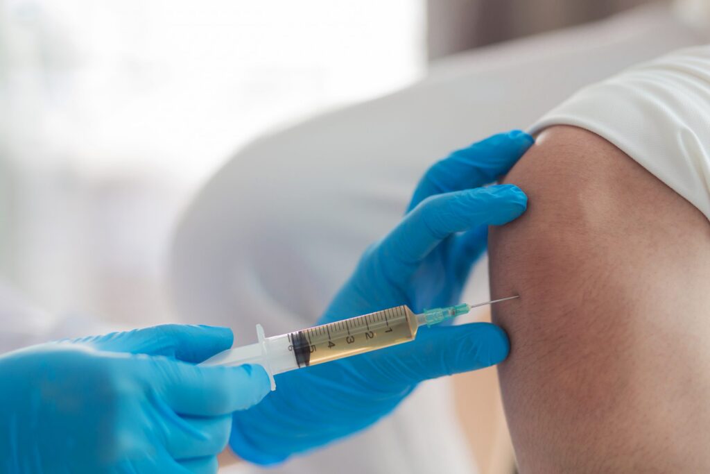 closeup of hypodermic needle drawing fluid from knee