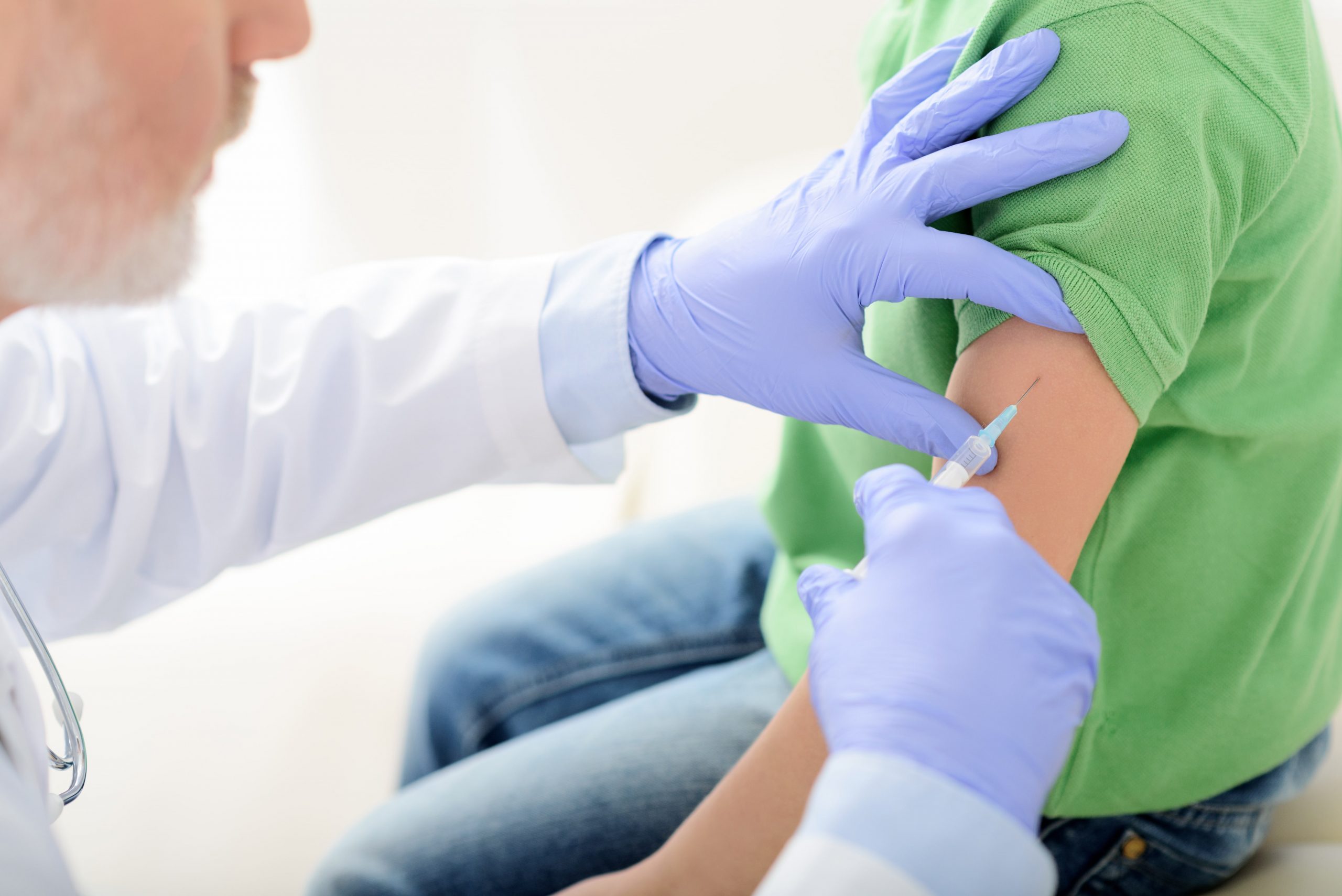 close up of physician administering vaccine in patient's arm with hypodermic needle