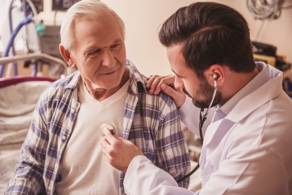 physician listening to senior male patient's heart with stethoscope