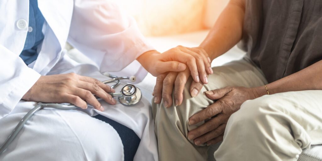 physician's hand resting on patient's in comforting manner