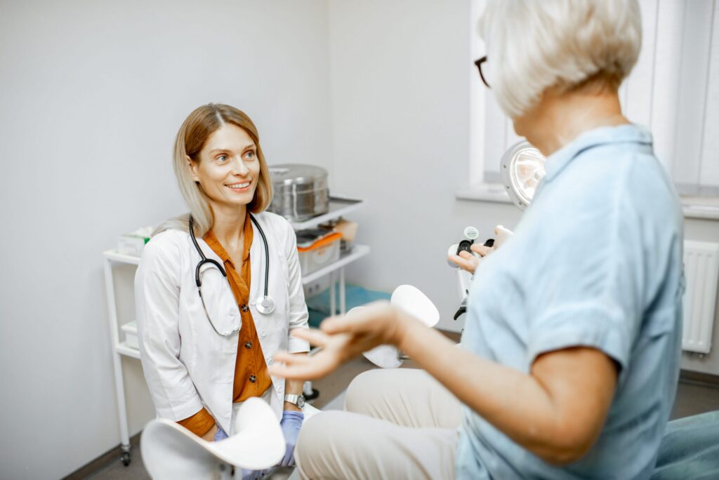 seated, smiling female physician listening to patient