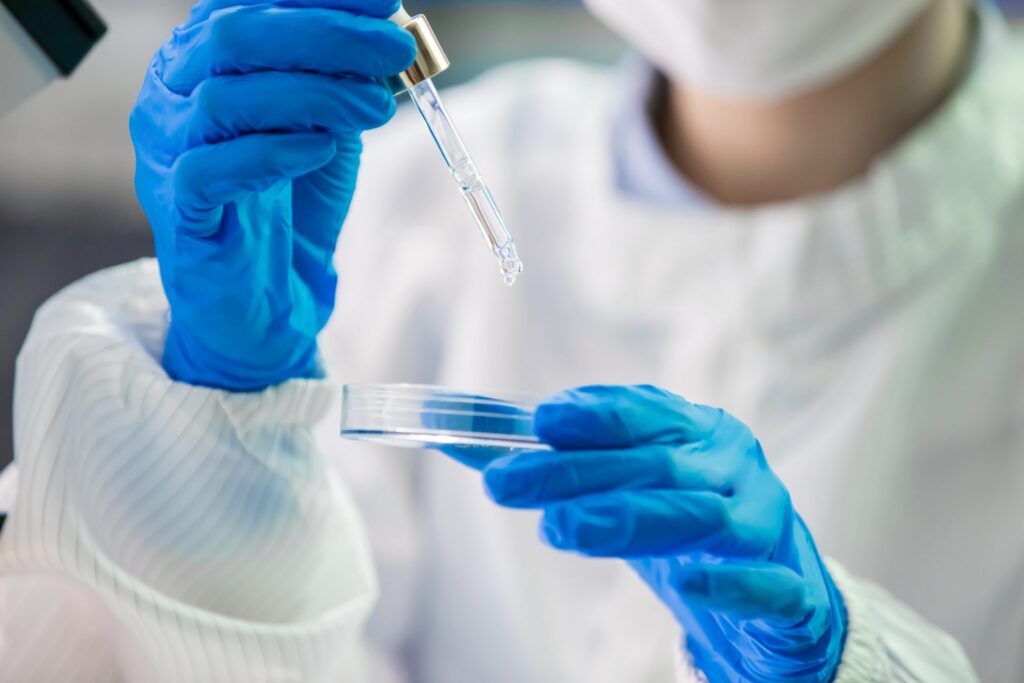closeup of lab technician dropping fluid in petri dish