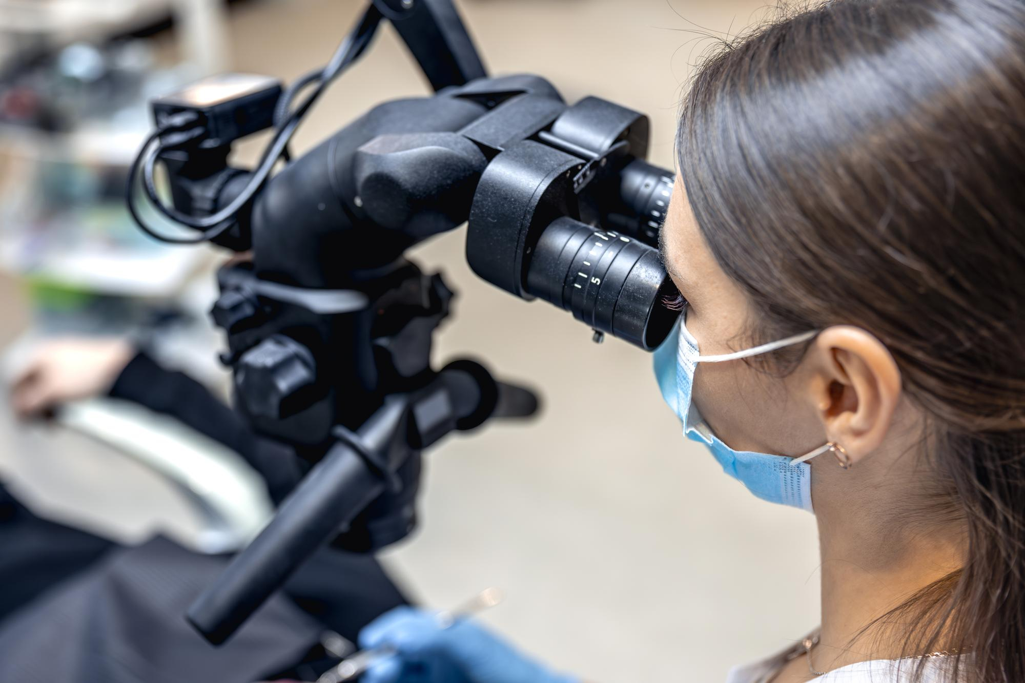 young female examining patient with colposcope